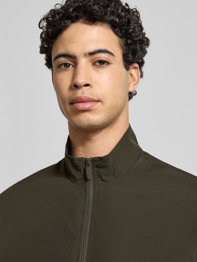 Männermodel trägt Regular Fit Jacke mit Stehkragen Modell 'Charge' von JACK & JONES in Oliv mit Reißverschluss, Nahaufnahme Oberkörper. Rückenlänge 66 cm, Schulterbreite 49 cm, Brustweite 50 cm, Ärmellänge 64 cm.