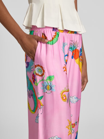 Frauenmodel trägt Stoffhose aus Viskose im Allover-Look von Milano Italy in pink mit bunten Mustern, Elastischer Bund, Nahaufnahme Oberkörper. Bundweite bei Größe 36: 38 cm, Innenbeinlänge bei Größe 36: 82 cm.