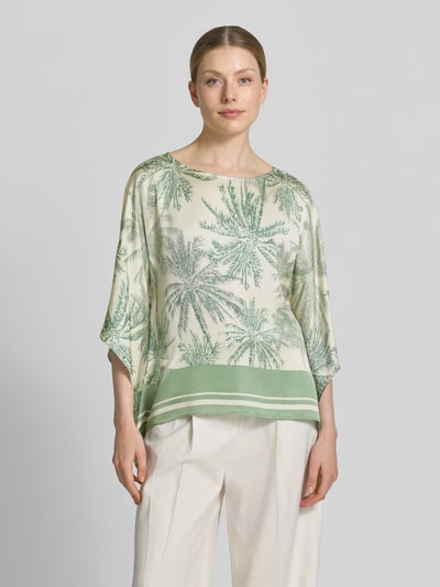 Frauenmodel trägt Relaxed Fit Kurzarmbluse aus reiner Viskose von s.Oliver BLACK LABEL mit grünem Palmenmuster, weiche Textur, Ganzkörperansicht von vorne.
