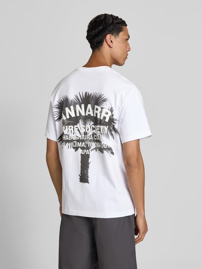Männermodel trägt Relaxed Fit T-Shirt mit Logo-Print von ANNARR aus Reine Baumwolle, Weiß mit Palmenmotiv, Rückenlänge 72 cm, Ganzkörperansicht Rückansicht.
