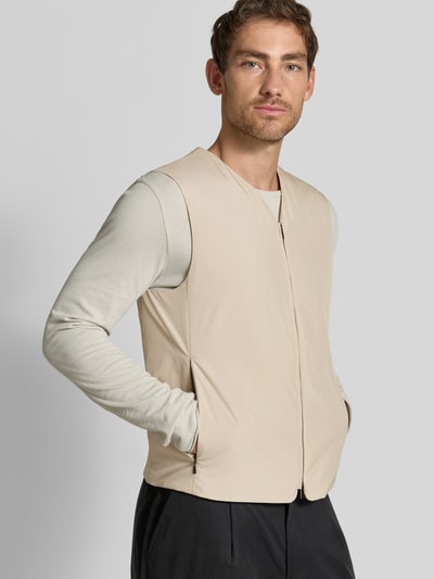 Männermodel trägt beigefarbene Regular Fit Weste mit V-Ausschnitt Modell 'Marve' von Tiger of Sweden, Zweiwege-Reißverschluss, Eingrifftaschen, Ganzkörperansicht von vorne. Rückenlänge 63 cm, Schulterbreite 41 cm, Brustweite 52 cm.