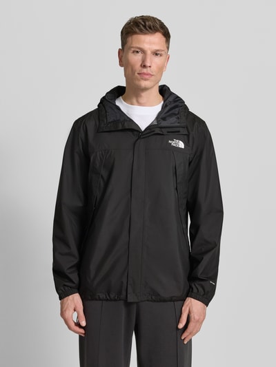 Männermodel trägt schwarze The North Face Jacke mit Kapuze, verdecktem Reißverschluss und Label-Print, Ganzkörperansicht von vorne.