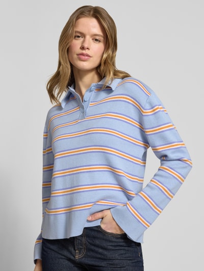 Vrouwenmodel draagt Regular Fit Poloshirt met viscose van Gina Tricot, lichtblauw met gestreept breisel, polokraag, lange mouw, vooraanzicht half-totale opname.
