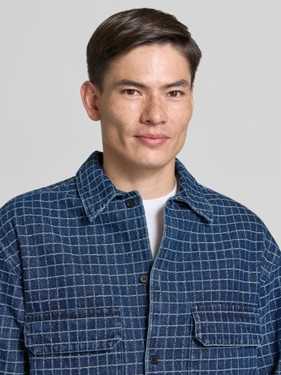 Męski model nosi Regular Fit Hemdjacke mit Viskose-Anteil Modell 'David' od Wood Wood, bawełniany miks z domieszką wiskozy, kratka w odcieniach niebieskiego, kołnierz kent, listwa guzikowa, kieszenie na piersi, kontekst: długość tyłu w rozmiarze M: 74 cm, ujęcie: zbliżenie górnej części ciała.