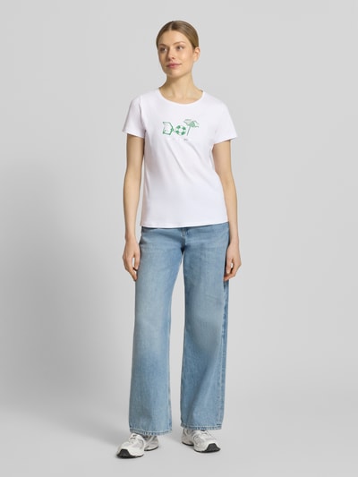 Frauenmodel trägt T-Shirt mit Motiv-Print und Rundhalsausschnitt von More & More aus Baumwoll-Elasthan-Mix, Regular-Fit, Rückenlänge 58 cm, Ganzkörperansicht von vorne.