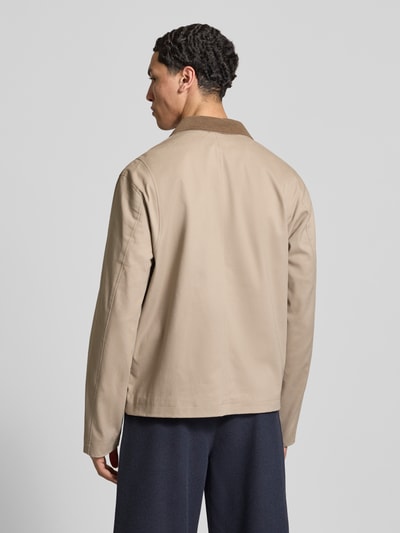 Męski model nosi beżową Jacke mit Umlegekragen Modell 'GRAHAM' von Jack & Jones, krój regular fit, widok całej sylwetki od tyłu. Długość pleców w rozmiarze M: 67 cm, szerokość ramion w rozmiarze M: 40 cm, szerokość klatki piersiowej w rozmiarze M: 58 cm, długość rękawa w rozmiarze M: 73 cm.
