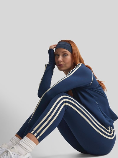 Frauenmodel trägt Slim Fit Sport-Leggings mit CLIMACOOL Technologie von adidas, dunkelblau mit weißen Streifen, adidas Training, Nahaufnahme Oberkörper.
