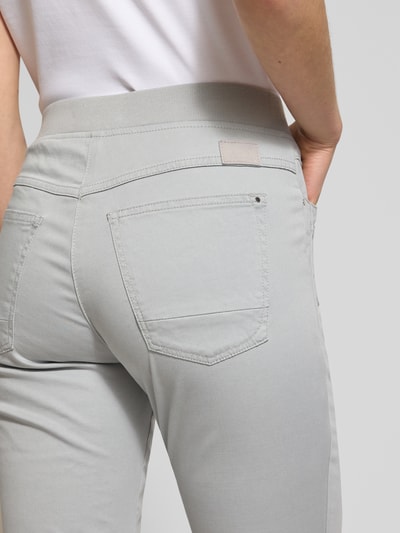 Kobiece modelka nosi spodnie materiałowe Relaxed Fit Stoffhose mit elastischem Bund Modell 'Pamina' od Raphaela By Brax, mieszanka bawełny, elastanowy pas, wpuszczane i tylne kieszenie, szerokość w rozmiarze 36K: 35 cm, długość wewnętrzna nogawki 73 cm, jasnoszary kolor, detaliczne ujęcie tylnej części.