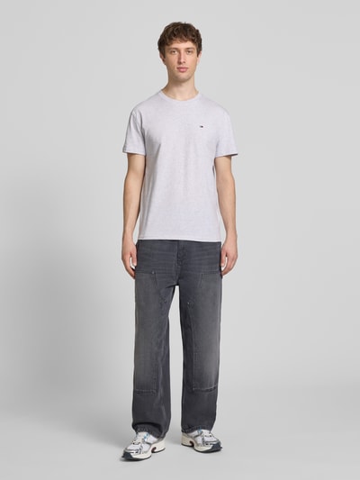 Männermodel trägt Regular Fit T-Shirt aus reiner Baumwolle von Tommy Jeans, Optik: Unifarben, Logo-Stitching, Ganzkörperansicht von vorne.
