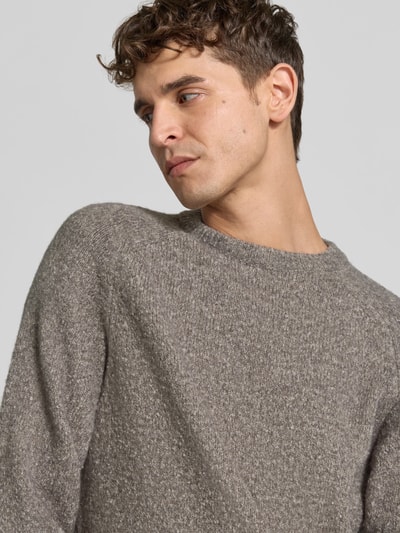 Męski model nosi Regular Fit Pullover mit Woll-Anteil od Closed, mieszanka bawełny i wełny, imitacja dzianiny, okrągły dekolt, elastyczne wykończenia, szaro-brązowa tekstura, Nahaufnahme górnej części ciała.