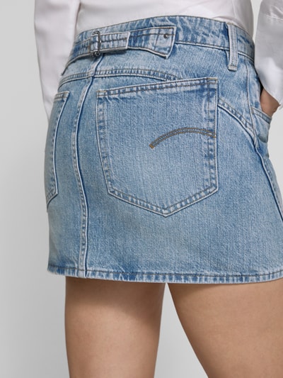 Frauenmodel trägt Minirock in Denim-Optik Modell 'Cinch' von G-Star Raw, Reine Baumwolle, Gesäß- und Eingrifftaschen, Knopf- und Reißverschluss, leicht ausgestellte Passform, Nahaufnahme Rückansicht.