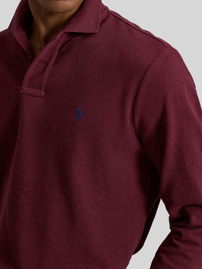 Männermodel trägt Regular Fit Poloshirt aus reiner Baumwolle von Polo Ralph Lauren in Dunkelrot mit feiner Struktur, Nahaufnahme Oberkörper. Herren Poloshirt von Polo Ralph Lauren