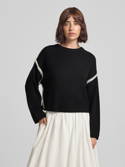 Frauenmodel trägt Strickpullover mit Rundhalsausschnitt und Kontraststreifen von Oui, Material-Mix mit Woll-Anteil, Relaxed Fit, Schwarz mit weißen Akzenten, Ganzkörperansicht von vorne.