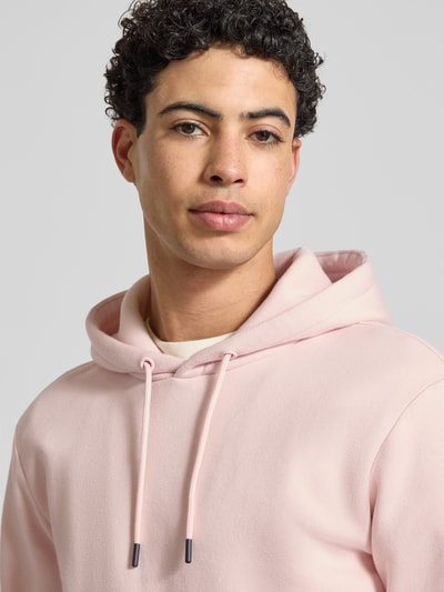 Männermodel trägt Regular Fit Hoodie aus Baumwoll-Mix Modell 'CERES' von Only & Sons in Rosa, Sweat-Optik, Nahaufnahme Oberkörper.