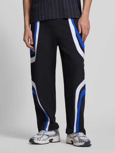 Männermodel trägt Relaxed Fit Sweatpants aus Baumwoll-Mix Modell 'Nalotron' von Hugo Blue mit blauen und weißen Kontraststreifen, Ganzkörperansicht von vorne.
