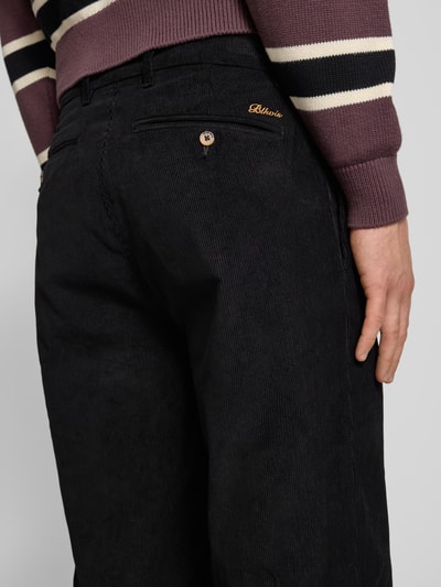 Männermodel draagt Cordhose met achterzakken Modell 'Script' van BLKVIS, zwart, wijde pijpen, katoenen ribstof, detailopname achterzijde.