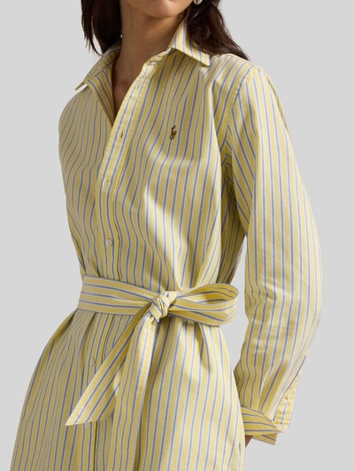 Frauenmodel trägt Regular Fit Oxford-Hemdblusenkleid mit Gürtel von Polo Ralph Lauren aus gelber Baumwolle mit blauen Streifen, Logo-Stitching, Taillengürtel und seitlichen Eingrifftaschen, Nahaufnahme Oberkörper.