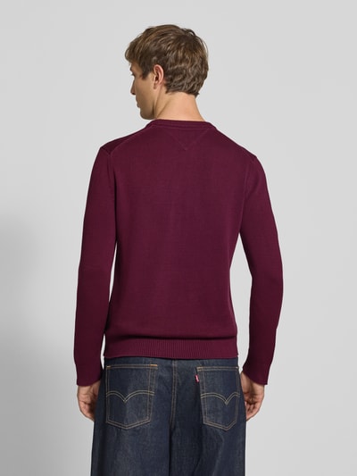 Männermodel trägt Slim Fit Pullover aus reiner Baumwolle von Tommy Jeans in Bordeaux, unifarben, Struktur-Strick, Ganzkörperansicht Rückansicht.