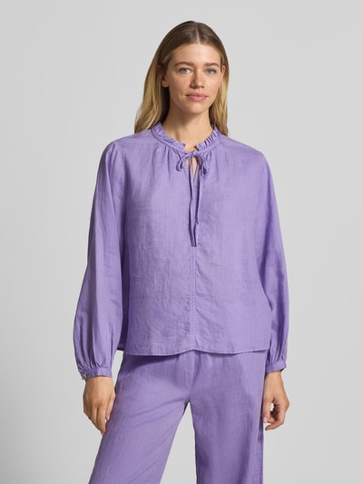 Frauenmodel trägt Leinenbluse mit Serafino-Kragen und Schnürung von Emily Van den Bergh, violett, Loose-Fit, reine Leinen, Ganzkörperansicht von vorne. Rückenlänge 59 cm, Ärmellänge 59 cm, Sportmanschetten, Größe 36, weiche Textur.