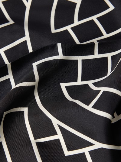 Produktfoto, Seidentuch aus reiner Seide von Anine Bing mit dreieckigem Design, eingefassten Abschlüssen, Kontraststreifen und Label-Detail, schwarze und weiße geometrische Muster, glatte und leicht glänzende Textur, Detailaufnahme, Breite bei Größe 1: 62 cm.