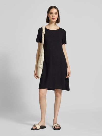 Frauenmodel trägt Relaxed Fit Kleid aus Viskose-Mix Modell 'Tara' von ZABAIONE in Schwarz mit Rundhalsausschnitt, Kurzärmelig, Ganzkörperansicht von vorne, Rückenlänge 96 cm, Brustweite 49 cm, Ärmellänge 21 cm.