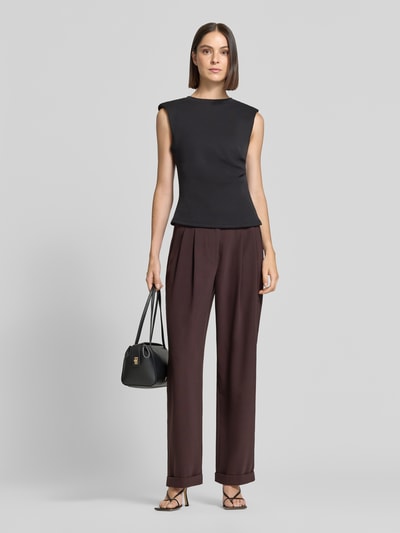 Frauenmodel trägt Relaxed Fit Stoffhose mit Kellerfalten von Armani Exchange in Dunkelbraun mit umgeschlagenen Beinabschlüssen, Kombi mit schwarzem Oberteil und Handtasche, Ganzkörperansicht von vorne. Damen Stoffhose, Knopf- und Reißverschluss, Eingriff- und Gesäßtaschen, Bundweite 42 cm, Innenbeinlänge 78 cm.