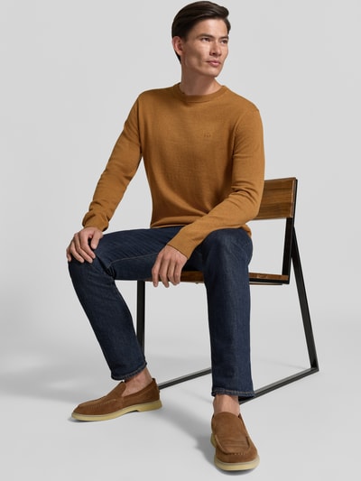 Männermodel trägt Regular Fit Pullover aus reiner Baumwolle von Tom Tailor in Braun, kombiniert mit Jeans, Ganzkörperansicht von vorne. Herren Pullover von Tom Tailor.
