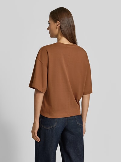Frauenmodel trägt Oversized T-Shirt aus reiner Baumwolle von s.Oliver RED LABEL in Braun, kombiniert mit dunkler Jeans, Ganzkörperansicht Rückansicht.