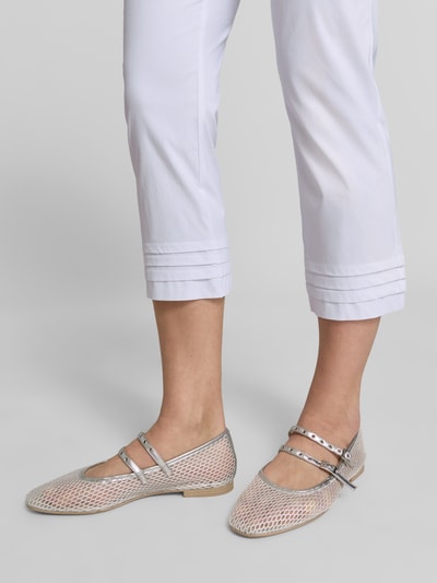 Kobieta nosi Caprihose aus Viskose-Mix Modell 'Ina' od STEHMANN, krój slim fit, białe z drapowaniami, Szerokość w rozmiarze 36: 38 cm, Długość nogawki wewnętrznej w rozmiarze 36: 59 cm, zbliżenie na dolną część nóg.
