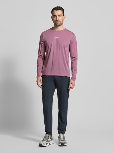 Mannenmodel draagt Funktionsshirt mit Logo und Rundhalsausschnitt van Salomon in regular fit, lange mouwen, ruglengte maat M 70 cm, geheelbeeld vooraanzicht.