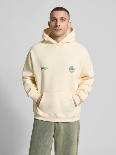 Männermodel trägt Hoodie mit Logo-Prints Modell 'Sunday Miles' von ANOTHER COTTON LAB, beige, Baumwoll-Mix, Loose Fit, Ganzkörperansicht von vorne.