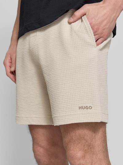 Männermodel trägt Regular Fit Sweatshorts aus Baumwoll-Mix Modell 'AUSTIN' von HUGO, Optik: Unifarben, Waffelstruktur, seitliche Eingrifftaschen, Tunnelzug, Bundabschluss: elastisch, Material: Baumwoll-Mix, Nahaufnahme Oberschenkel.