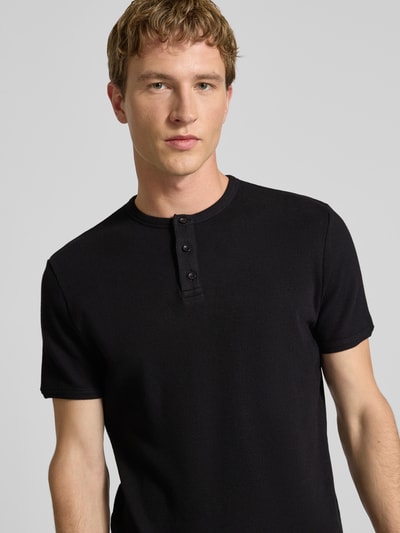 Männermodel trägt T-Shirt mit kurzer Knopfleiste von REVIEW, Schwarz, fein gerippter Baumwoll-Mix, körpernah, Nahaufnahme Oberkörper.