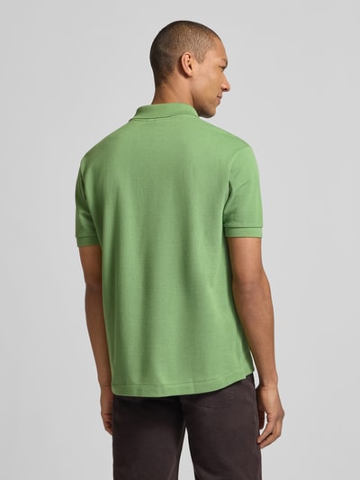 Männermodel trägt Regular Fit Poloshirt aus reiner Baumwolle von Lacoste, unifarben grün, Piqué-Textur, Ganzkörperansicht Rückansicht.