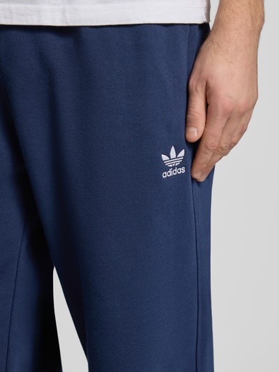 Männermodel trägt Wide Fit Sweatpants mit elastischem Bund von adidas Originals in Dunkelblau, Baumwoll-Mix, Nahaufnahme Oberschenkel.