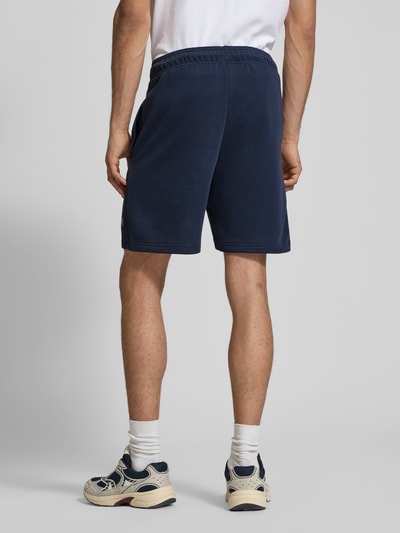 Männermodel trägt Sweatshorts mit Logo und elastischem Bund von CHAMPION in Dunkelblau, Baumwoll-Mix, Rückenansicht, Ganzkörperansicht Rückansicht.