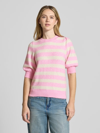 Frauenmodel trägt Regular Fit Strickpullover mit Crew Neck Modell 'DOFFY' von Vero Moda, Optik: Unifarben, Strickoptik, Label-Stitching-Applikation, Rundhals, 1/2-Arm, gerippte Abschlüsse, Materialverarbeitung: Strick, Ganzkörperansicht von vorne.