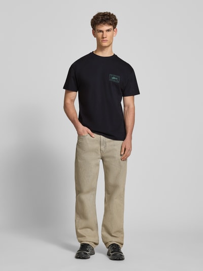 Männermodel trägt Regular Fit T-Shirt mit Logo-Print von BLKVIS in Schwarz aus Reine Baumwolle, Rundhalsausschnitt, Ganzkörperansicht von vorne. Rückenlänge bei Größe M: 67 cm.