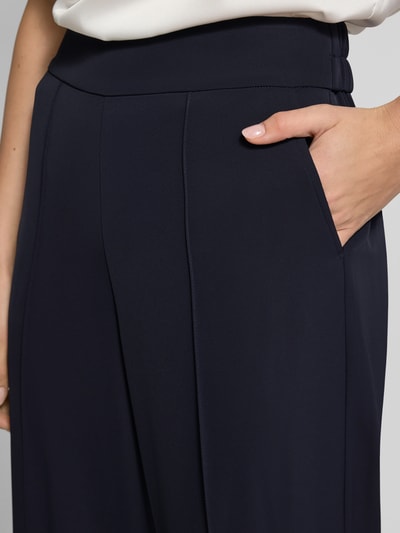 Kobiece modelka nosi 'Stoffhose mit elastischem Bund' od comma, granatowy materiał z elastycznym pasem, luźny krój, detal kieszeni, zbliżenie na biodra