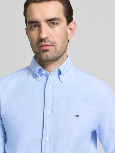 Männermodel trägt Regular Fit Freizeithemd aus reiner Baumwolle von Tommy Hilfiger in hellblau mit Allover-Muster, Nahaufnahme Oberkörper.