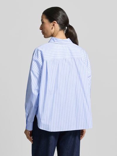 Frauenmodel trägt Oversized Hemdbluse aus reiner Baumwolle Modell 'AUREO' von Weekend Max Mara, blau-weiß gestreift, Ganzkörperansicht Rückansicht.
