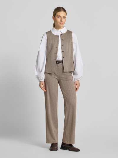 Frauenmodel trägt Weste mit Viskose-Anteil Modell 'Bonnie' von FREE/QUENT in Beige mit Knopfleiste, taillierte Passform, Ganzkörperansicht von vorne. Elastischer Material-Mix, sichtbare Struktur, Kombination mit weißer Bluse und Hose, Kontext: Rückenlänge 52 cm, Schulterbreite 36 cm, Brustweite 48 cm bei Größe S.