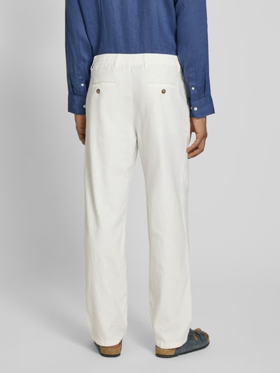 Männermodel trägt Loose Fit Leinenhose mit Tunnelzug Modell 'BRODY' von Selected Femme, kremowy bio-bawłniano-lniany flammgarn, tylnie kieszenie z guzikiem, widok całej sylwetki z tyłu.