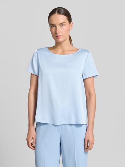 Frauenmodel trägt Blusenshirt mit Rundhalsausschnitt und abgerundetem Saum von Rinascimento, Material-Mix mit Stretch-Anteil, Loose-Fit, Rückenlänge bei Größe S 52 cm, hellblau, glatte Textur, Ganzkörperansicht von vorne.