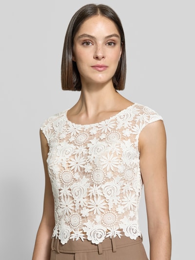 Frauenmodel trägt Cropped Spitzentop mit Rundhalsausschnitt von Luxuar aus weißer Spitze, Slim Fit, feine Blumenstruktur, Nahaufnahme Oberkörper.