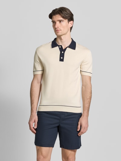 Männermodel trägt Slim Fit Poloshirt mit Logo-Stitching von Gant in Beige mit navyfarbenem Kragen, kurze Knopfleiste, Ganzkörperansicht von vorne