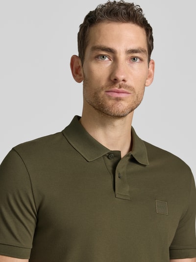 Męski model trägt Slim Fit Poloshirt aus Baumwoll-Mix Modell 'PASSENGER' von BOSS Orange, jednokolorowy, naszywka z logo, kołnierzyk polo, zapięcie na 2 guziki, krótki rękaw; mieszanka bawełny; zbliżenie na górną część ciała z przodu.