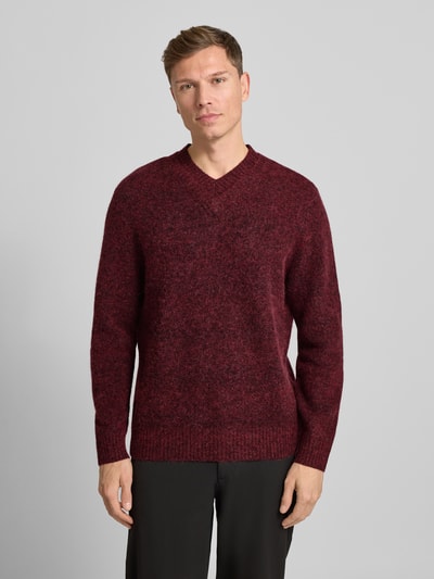 Männermodel trägt Strickpullover mit V-Ausschnitt Modell 'FLOYD' von Samsøe Samsøe in Dunkelrot, Woll-Mix, Relaxed Fit, Ganzkörperansicht von vorne