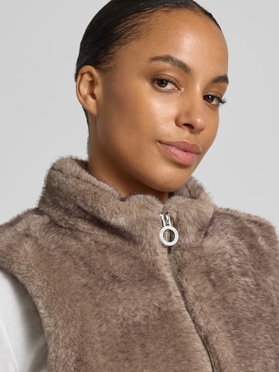 Kobiece modelka nosi kamizelkę Regular Fit Weste aus Kunstfell od FUCHS SCHMITT, sztuczne futro, stójka, zamek błyskawiczny dwustronny, Długość tyłu w rozmiarze 36: 55 cm, Szerokość ramion w rozmiarze 36: 42 cm, Szerokość klatki piersiowej w rozmiarze 36: 47 cm, jasnobrązowa, miękka faktura, zbliżenie na górną część ciała