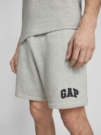 Männermodel trägt Sweatshorts mit elastischem Bund von GAP aus grauem Baumwoll-Mix mit Logo, Nahaufnahme Oberschenkel. Relaxed-Fit.